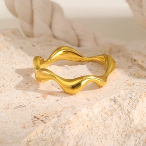 Close-up of golden irregular wavy ring with high-polished finish on natural stone