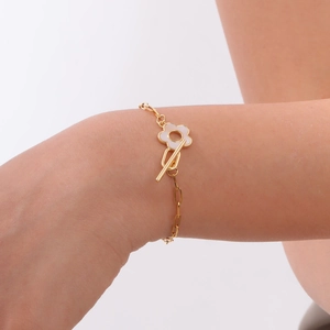 Detail of a gold stainless steel bracelet featuring a white shell flower and OT clasp toggle