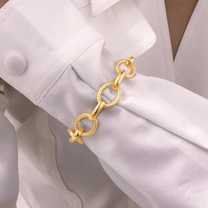 Detail of 18K gold intertwined chain links with twisted texture on white shirt sleeve