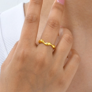Polished gold stainless steel irregular wave ring shown as a minimalist accessory on finger