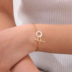 Detailed close-up of gold OT clasp bracelet featuring a white enamel ring on wrist