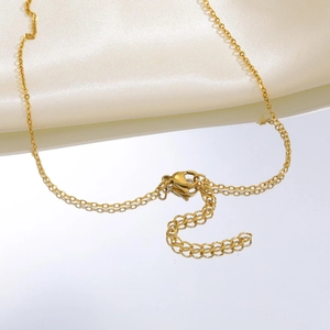 Détail d'un collier doré avec fermoir mousqueton et chaînette sur soie blanche