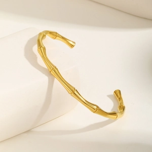Detail showing high-polished 18K gold bamboo-style cuff bangle on geometric stone