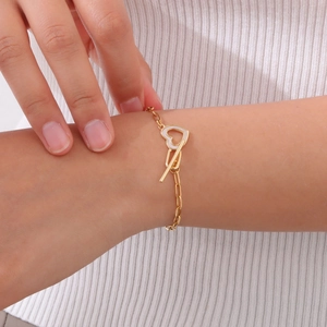 Close-up of gold heart pendant bracelet with a toggle clasp worn on a female wrist