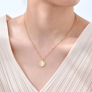 Collier doré avec pendentif croix en nacre et cristaux sur un mannequin féminin