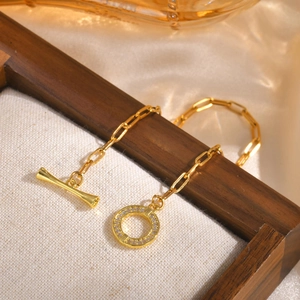 Detail of gold paperclip chain bracelet featuring a shimmering zircon-studded OT clasp closure