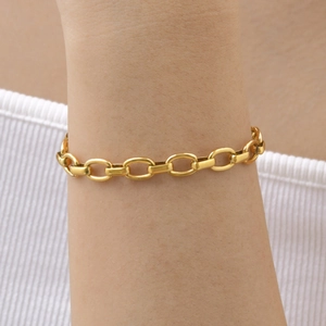 Gros plan d'un bracelet gourmette épais en plaqué or 18 carats sur le poignet d'une femme