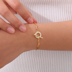 Detail of gold OT clasp bracelet with sparkling zircon stones worn by a model