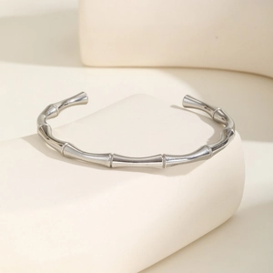 Close-up of a silver C-shaped bamboo node bracelet with polished mirror finish