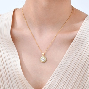Gros plan d'un collier doré avec pendentif rond en nacre blanche en forme de trèfle