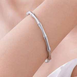 Detail view of a silver C-shaped bamboo texture bangle worn on a female wrist