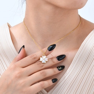 Gros plan d'un collier trèfle doré avec incrustation en nacre blanche sur le clavicule