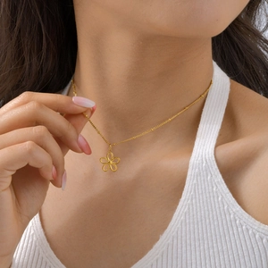 Detail of gold floral pendant necklace with bead chain on wearer for jewelry styling