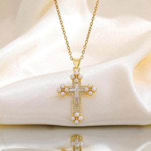 Gros plan détaillé du pendentif croix dorée avec perles et nacre sur tissu en soie