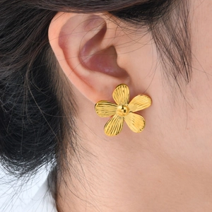 Details goldener Blumenohrringe mit radialer Textur und polierter Mitte