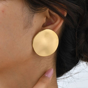 Macro view of a large gold stainless steel earring with an irregular hammered texture