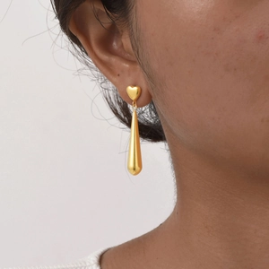 Boucles d'oreilles cœur dorées avec pendentif long élégant portées par un mannequin