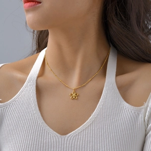 Golden stainless steel necklace featuring a hollow flower pendant on a female model