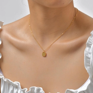 Close-up of 18K gold-plated necklace with a textured square pendant on female neck