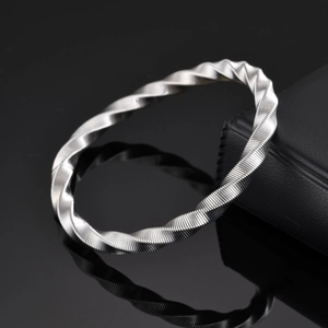 Bracelet jonc Mobius en acier inoxydable à texture torsadée sur fond noir minimaliste