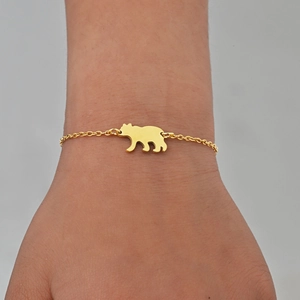 Gros plan d'un bracelet doré délicat avec pendentif ours sur un poignet féminin