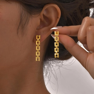 Fashionable gold stainless steel watchband chain drop earrings worn on a model