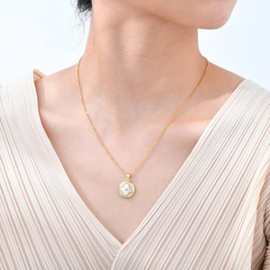 Collier doré avec pendentif trèfle en nacre et zircons porté par un mannequin