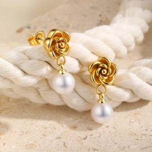 Golden camellia flower earrings with elegant white pearl drops on a natural stone base
