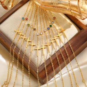 Goldene Edelstahl-Armbänder mit Kreuzanhängern und bunten Geburtssteinen in einer Box
