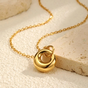Vue macro du pendentif cercle doré 18K avec finition miroir poli sur un fond pierre