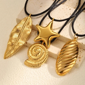 Dettaglio di ciondoli a foglia, stella e conchiglia placcati oro 18K su cordini neri