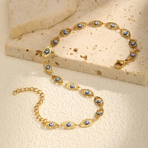 18K gold plated stainless steel evil eye anklet with blue enamel charms on stone texture