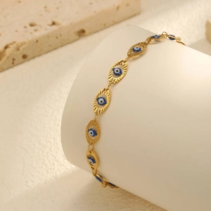 Detailed view of 18K gold stainless steel anklet with embossed blue evil eye charms
