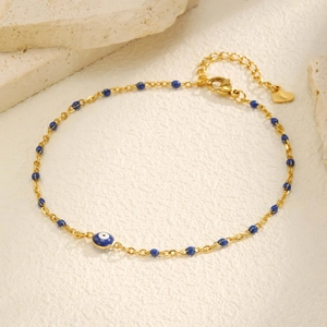 Détail du pendentif œil porte-bonheur et perles bleues sur chevillère en acier doré