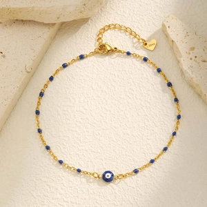 Détail du bracelet de cheville en acier doré avec perles bleues et pendentif œil bleu