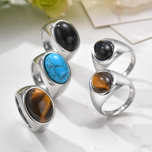 Set of five stainless steel rings with colorful oval natural stones on marble background