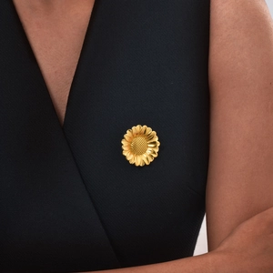 Broche fleur marguerite en or 18K sur robe noire pour un style de tenue élégante