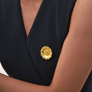 Détail d'une broche marguerite en or 18K avec pétales brossés sur revers sombre