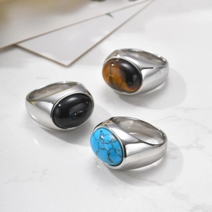 Close-up of three stainless steel rings featuring onyx, tiger eye and turquoise stones