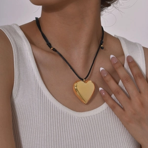 Detail of a hollow heart pendant on an adjustable black cord worn by a model