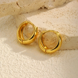 Macro shot of minimalist gold U-shaped hoop earrings on elegant textured stone background