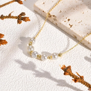 Elegant double-layer copper necklace with white pearls and gold beads on stone background