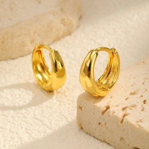Macro shot of chunky gold hoop earrings with high-polish finish on stone texture