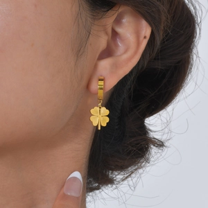 Gros plan de boucles d'oreilles trèfle à quatre feuilles dorées sur un mannequin