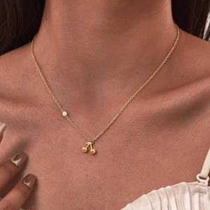 Macro detail of 18K gold-plated cherry pendant necklace with zircon on female neck