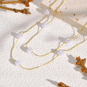 Close-up of elegant double-layer gold chain necklace with round white pearls on stone