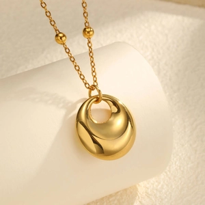 Gros plan d'un collier doré 18K avec pendentif géométrique et chaîne à billes en acier inox