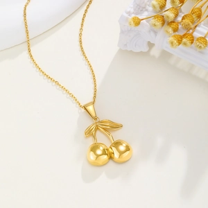 Detailed view of 18K gold cherry pendant with mirror polish on cream background