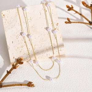 Detailed view of elegant double-layered gold pearl necklace on beige marble stone