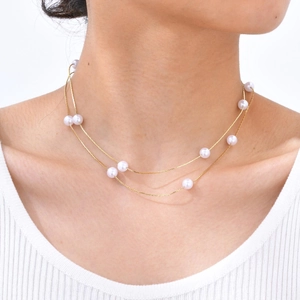 Detail of elegant double-layered gold chain necklace featuring polished white pearls